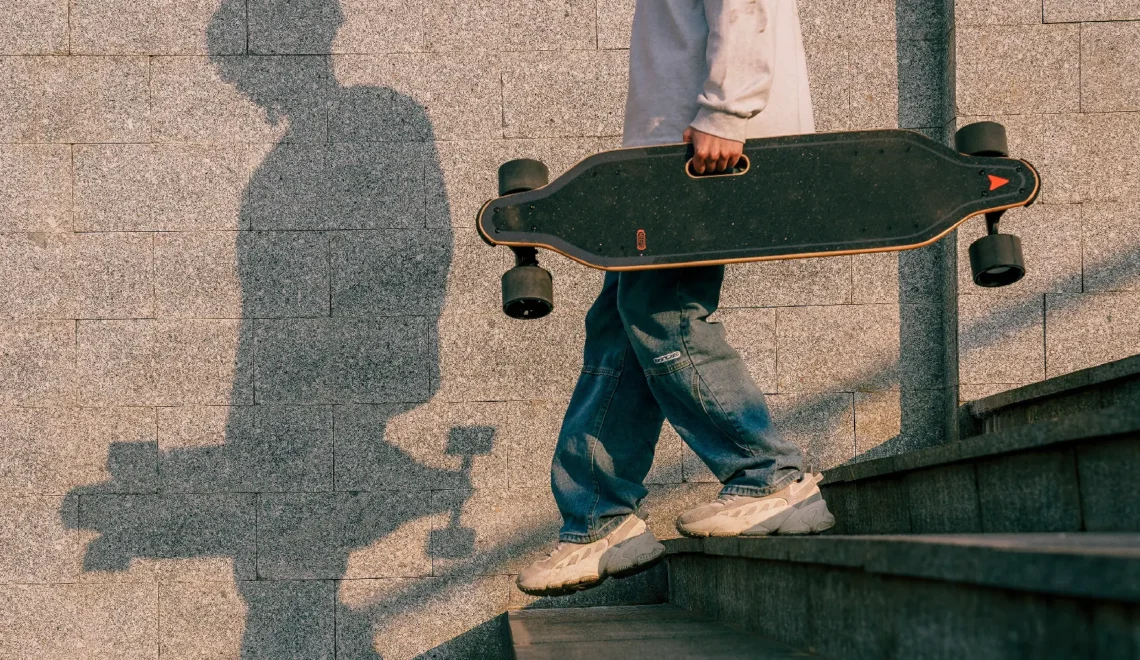 Man walking down steps while holding an electric skateboard